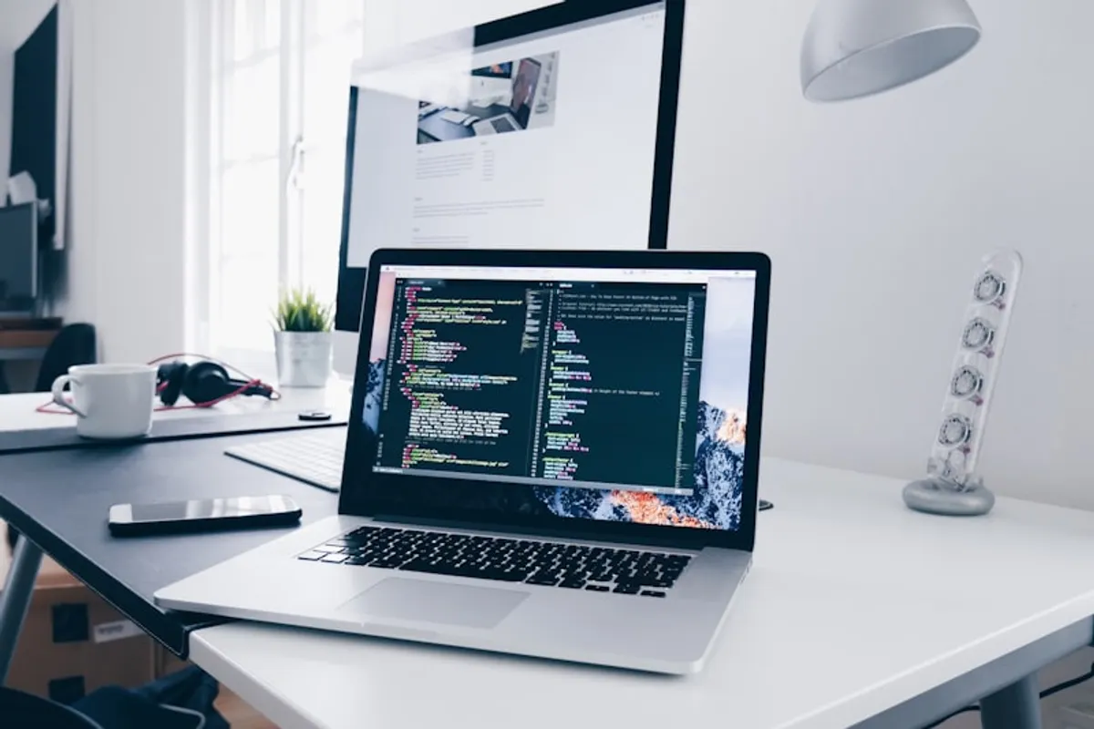 Web development workspace with code editor and laptop